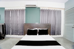 Un dormitorio con cama, cortinas, un equipo de aire acondicionado y una puerta cerrada.