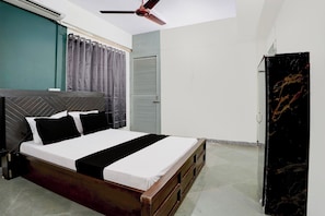 Un dormitorio con cama, ventilador de techo, armario y ventana con cortinas.