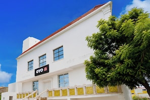 Un edificio blanco con techo rojo, un letrero que dice 'OYO Hotel Residencia Signature' y una escalera que lleva a la entrada.