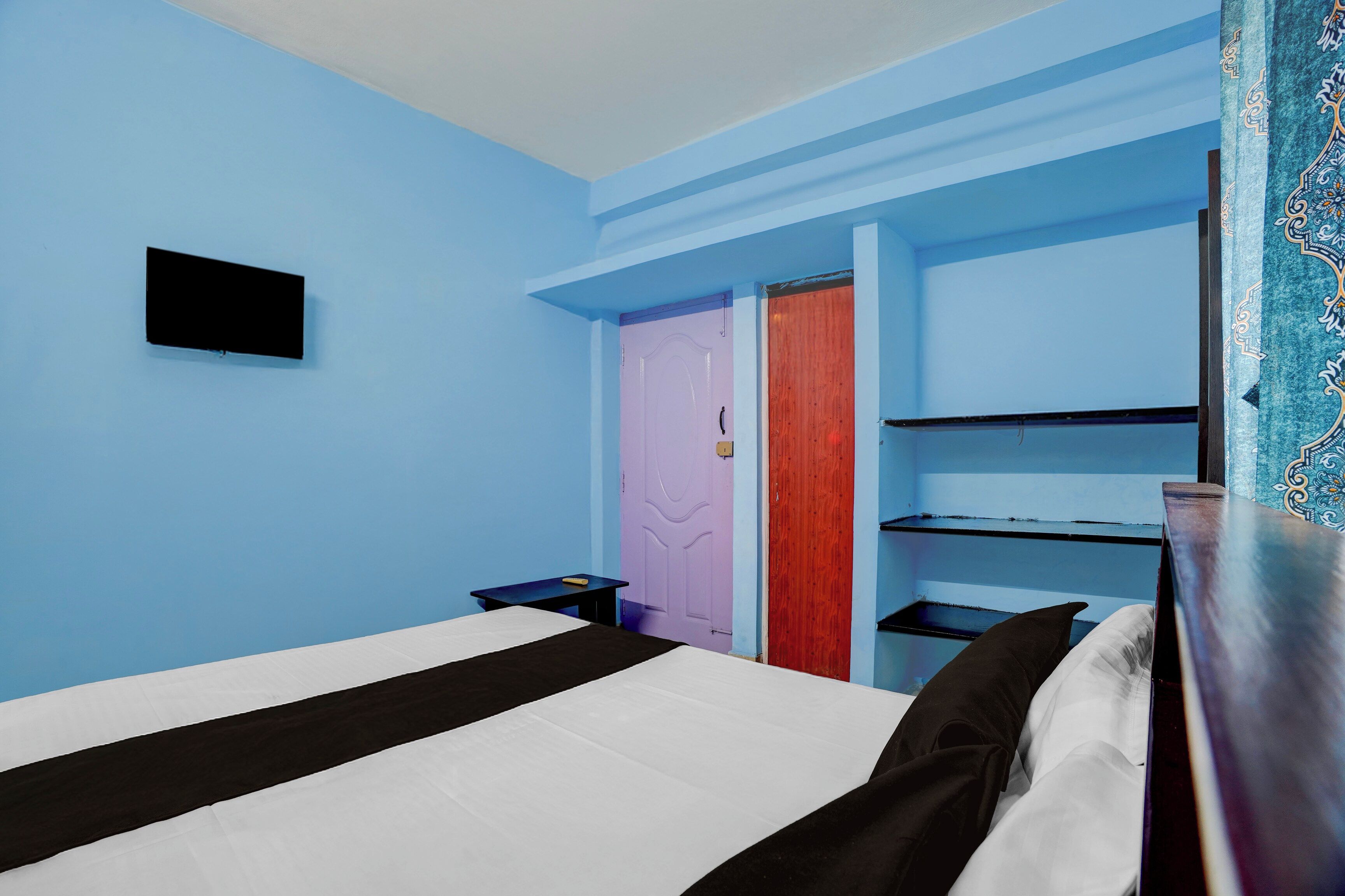 Een kamer met een bed, een tafeltje, een televisie en een deur.