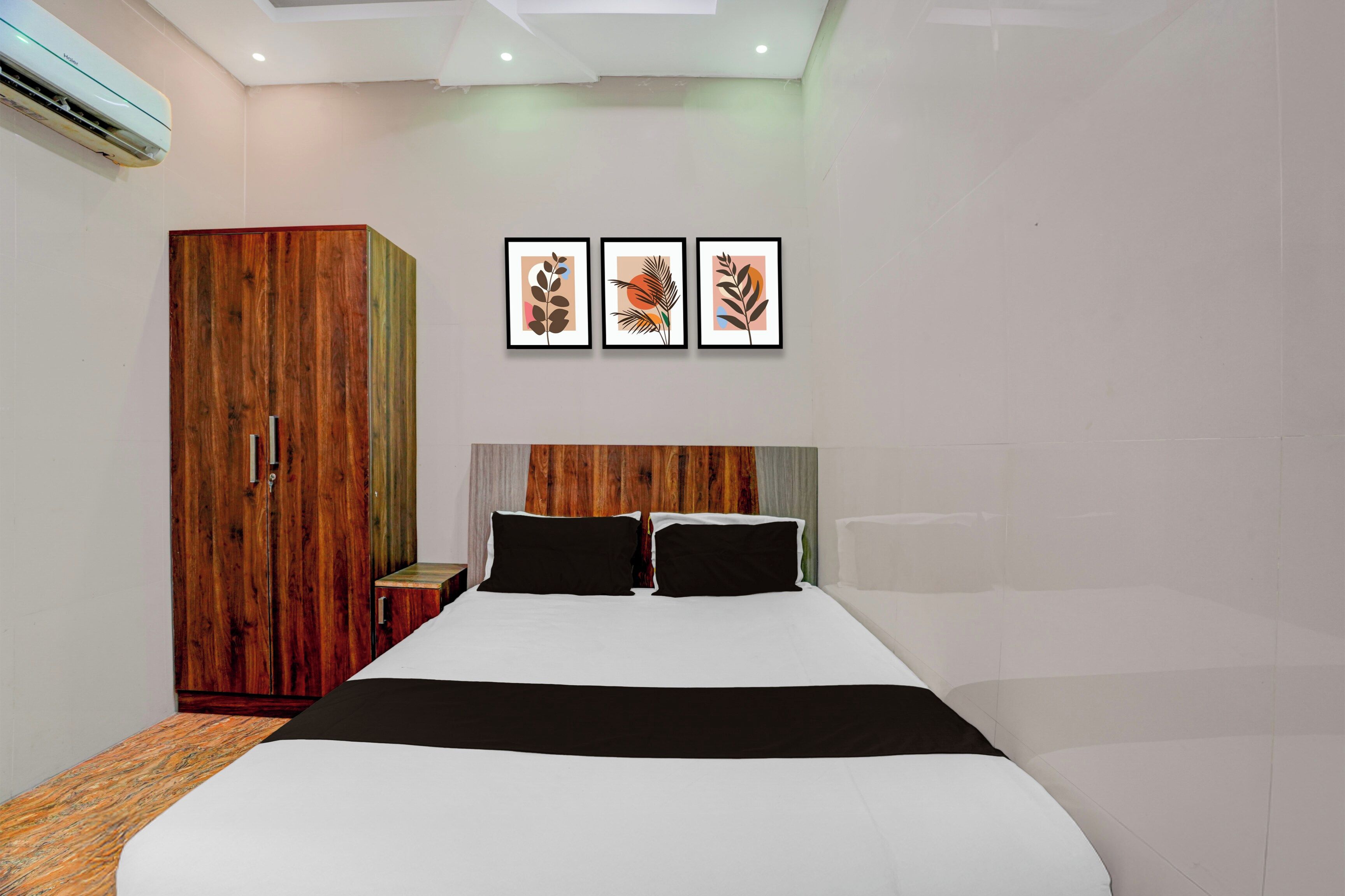 A bedroom with a bed, a wardrobe, and three framed artworks on the wall.