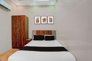 Un dormitorio con una cama, un armario y tres cuadros en la pared.