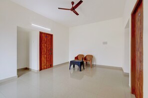 A room with a ceiling fan, a door with a number, a small table, and two chairs. - Hotel O DP RESIDENCY (Chennai)