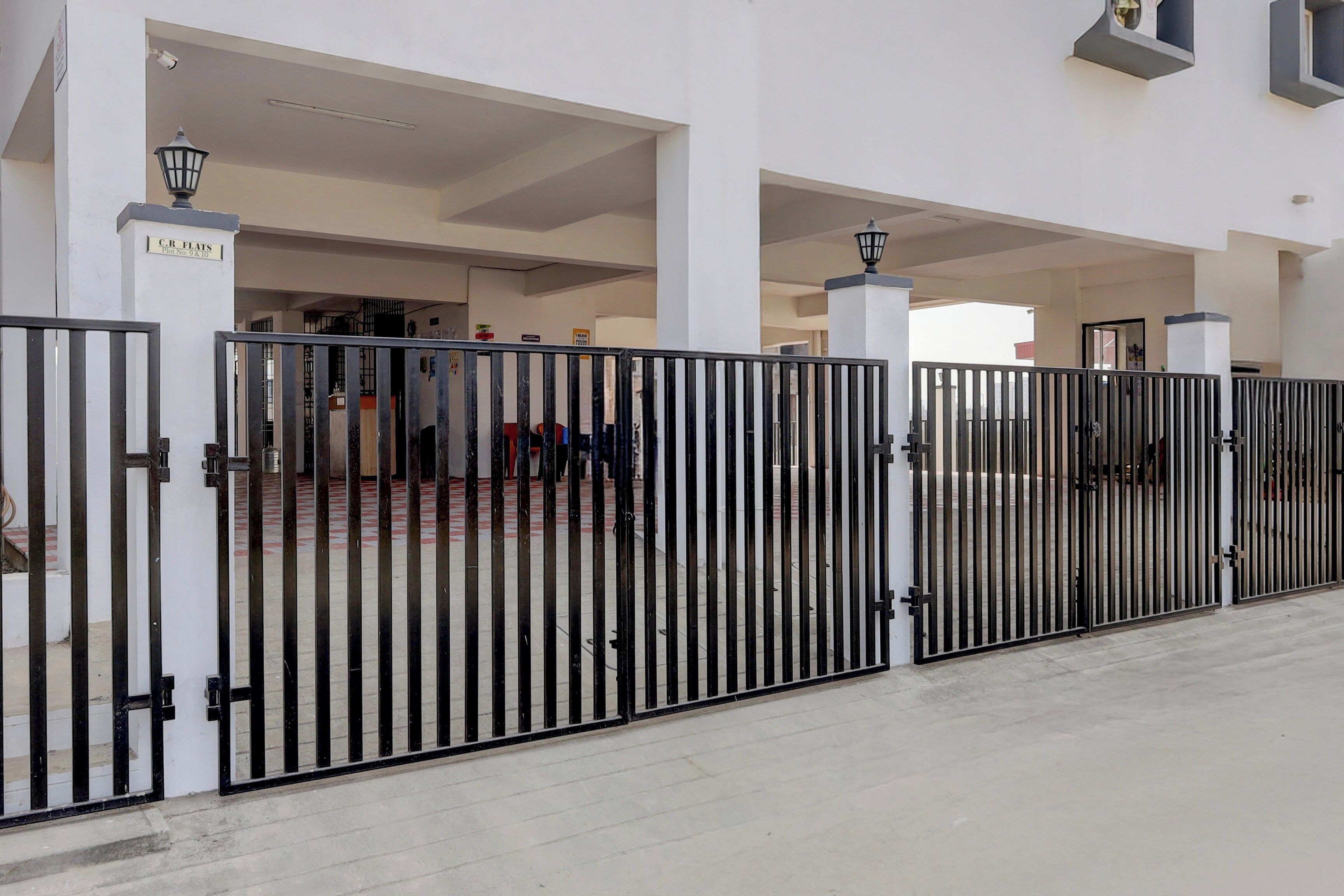 A gated entrance to a building with a tiled floor and a white exterior.