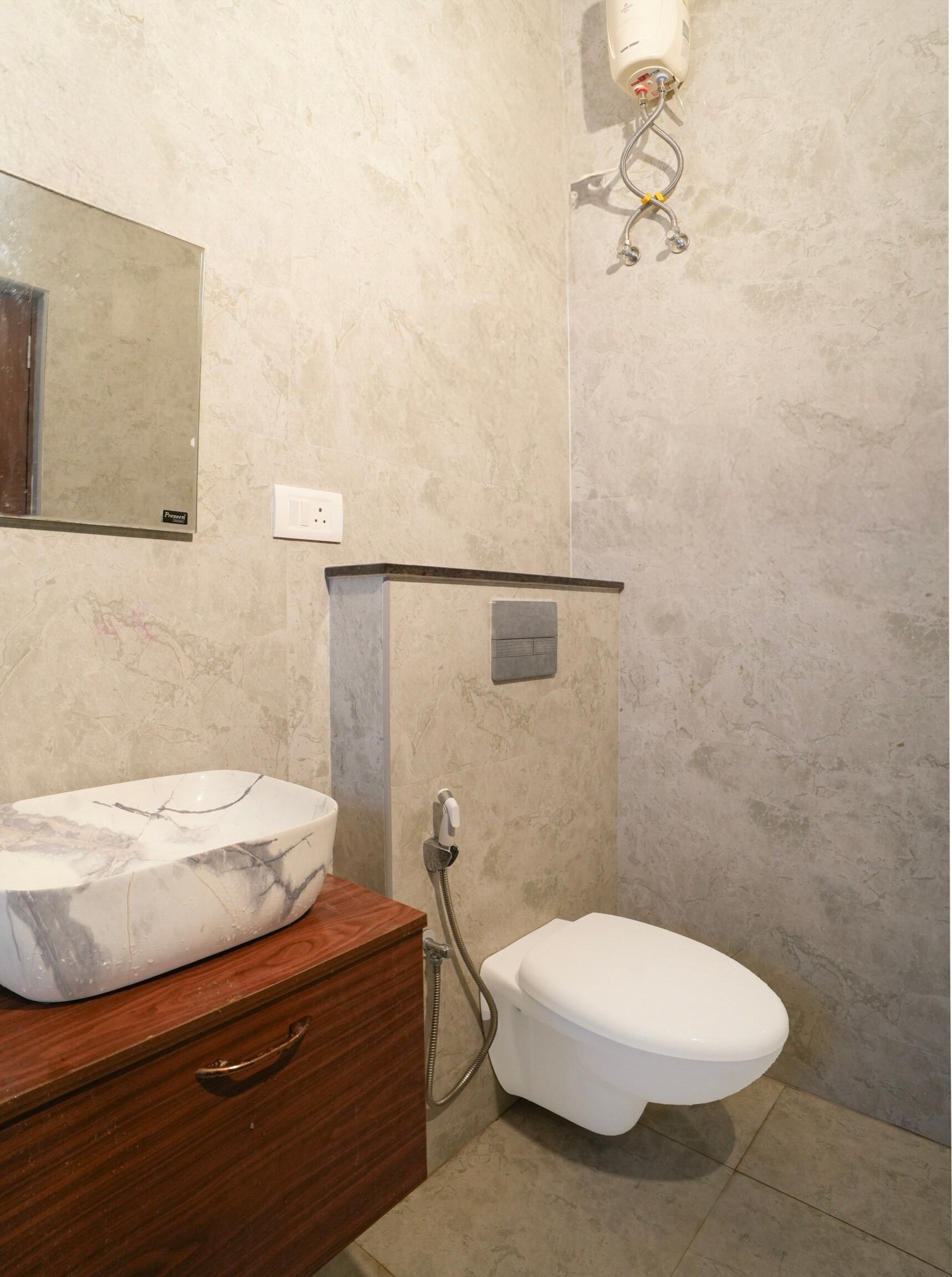 Un baño con lavamanos de mármol, inodoro y ducha.