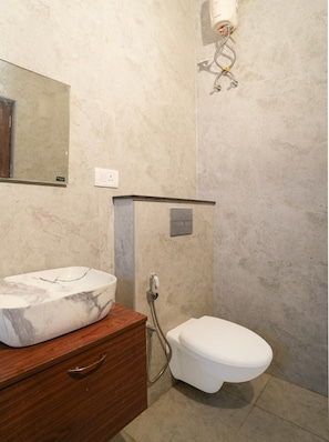 Un baño con lavamanos de mármol, inodoro y ducha.