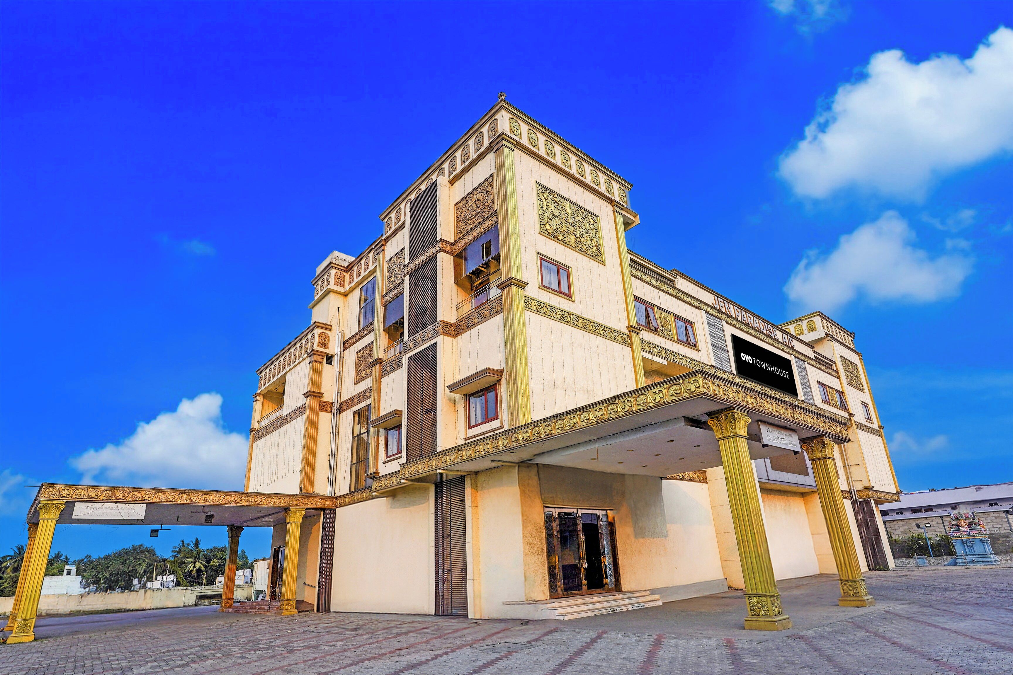 A multi-story building with a prominent entrance, columns, and a sign that reads 'OYO TOWNHOUSE'.