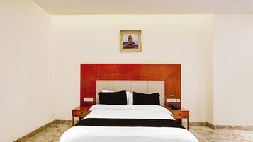 Una habitación de hotel con una cama, una mesita de noche, un cuadro en la pared y suelo de mármol.