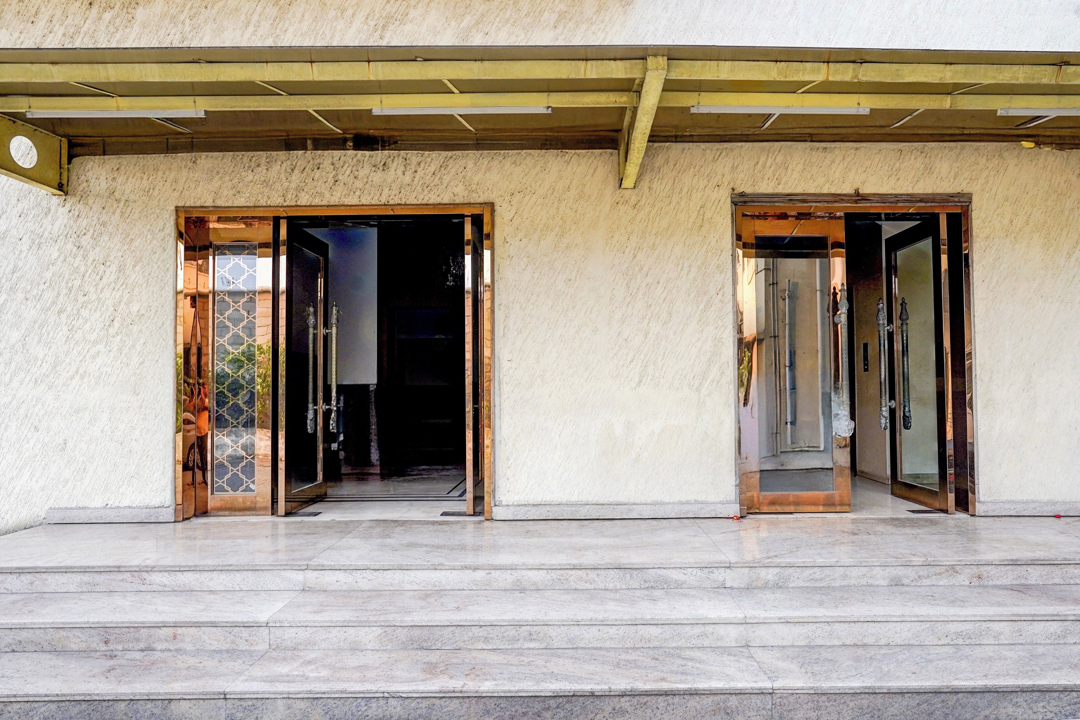 A building entrance with two open doors leading to a dark interior.