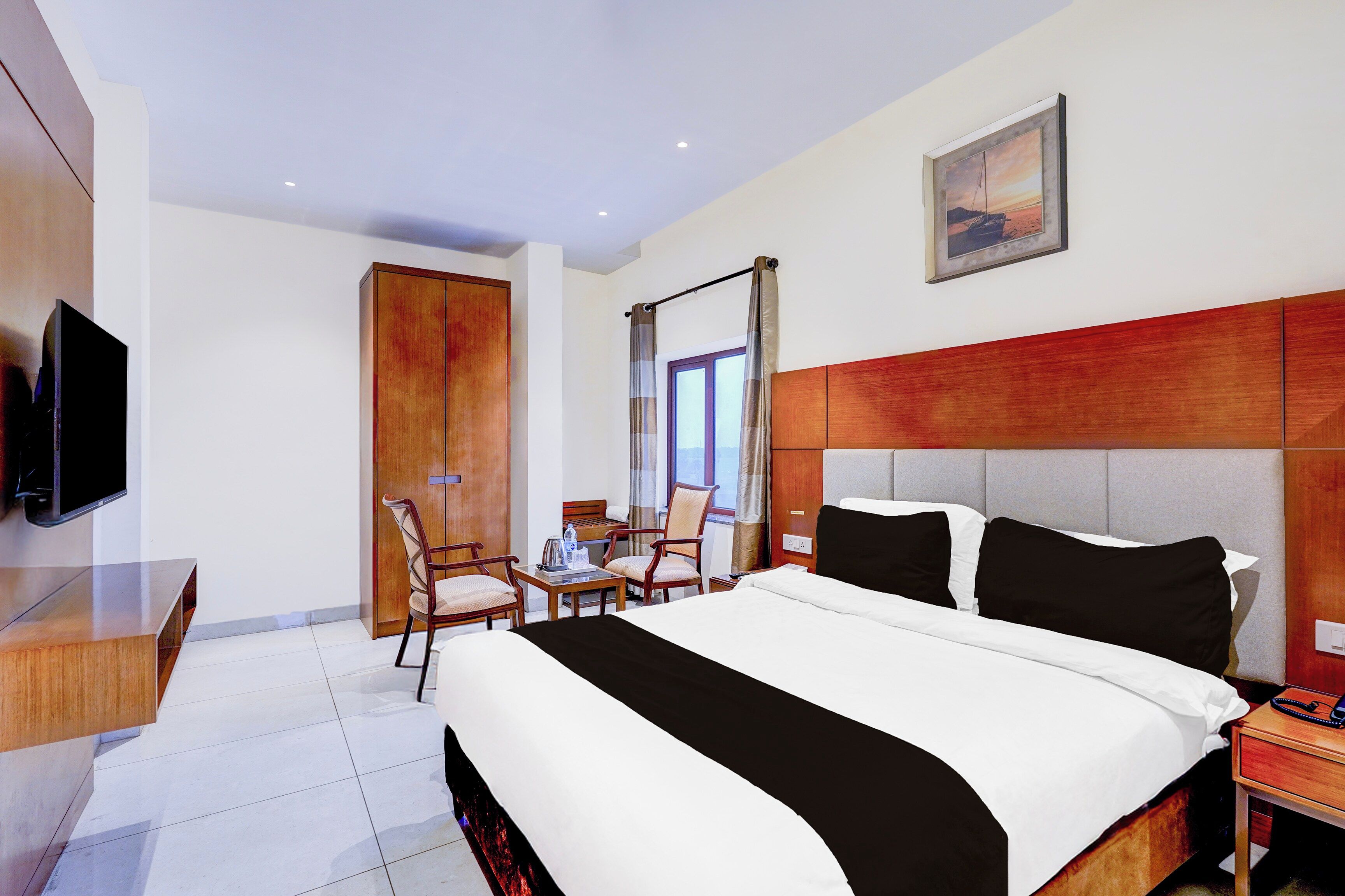 A hotel room with a large bed, a television, a desk, and a chair.