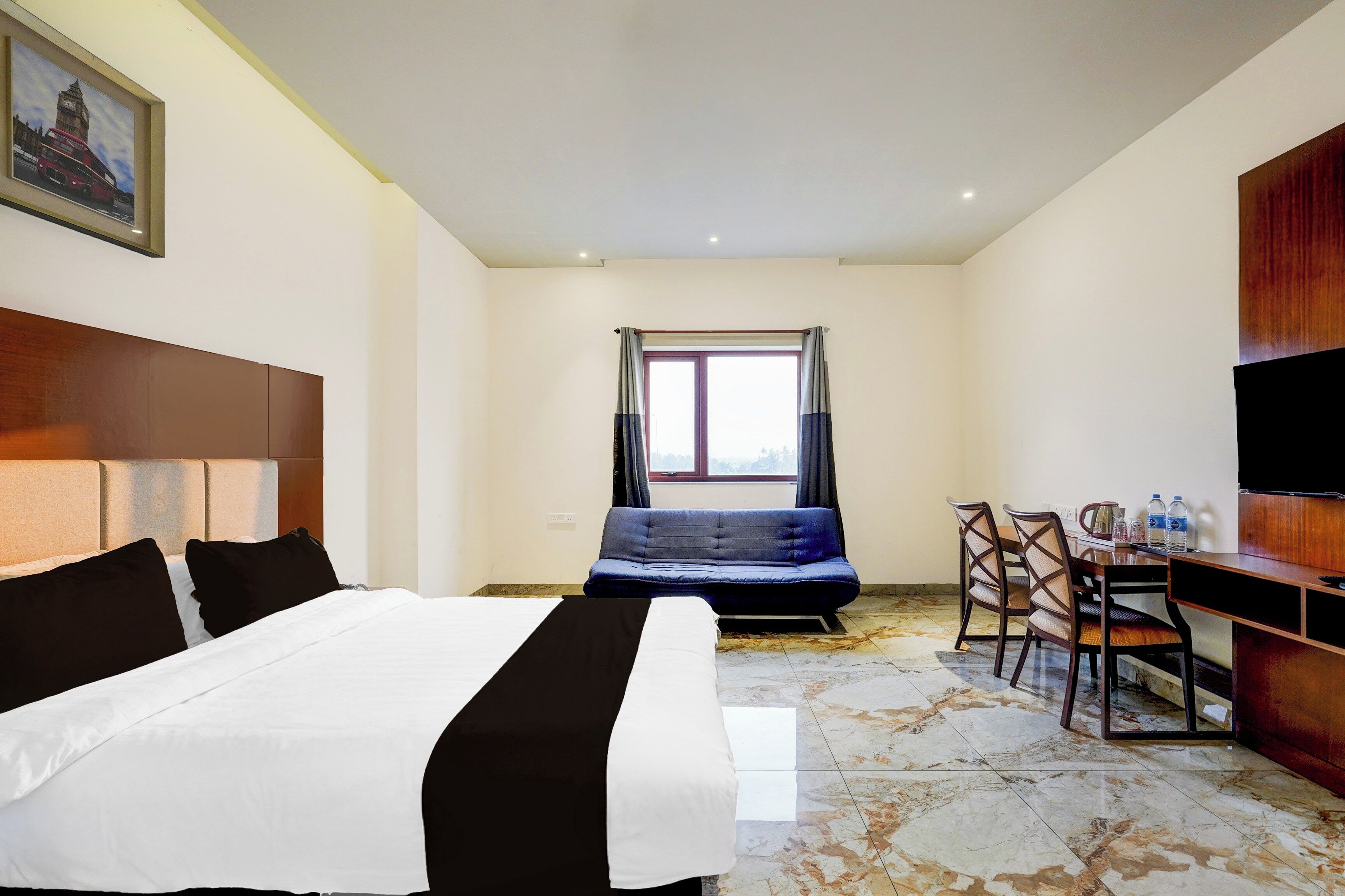 A hotel room with a bed, a desk, a chair, a television, and a window.