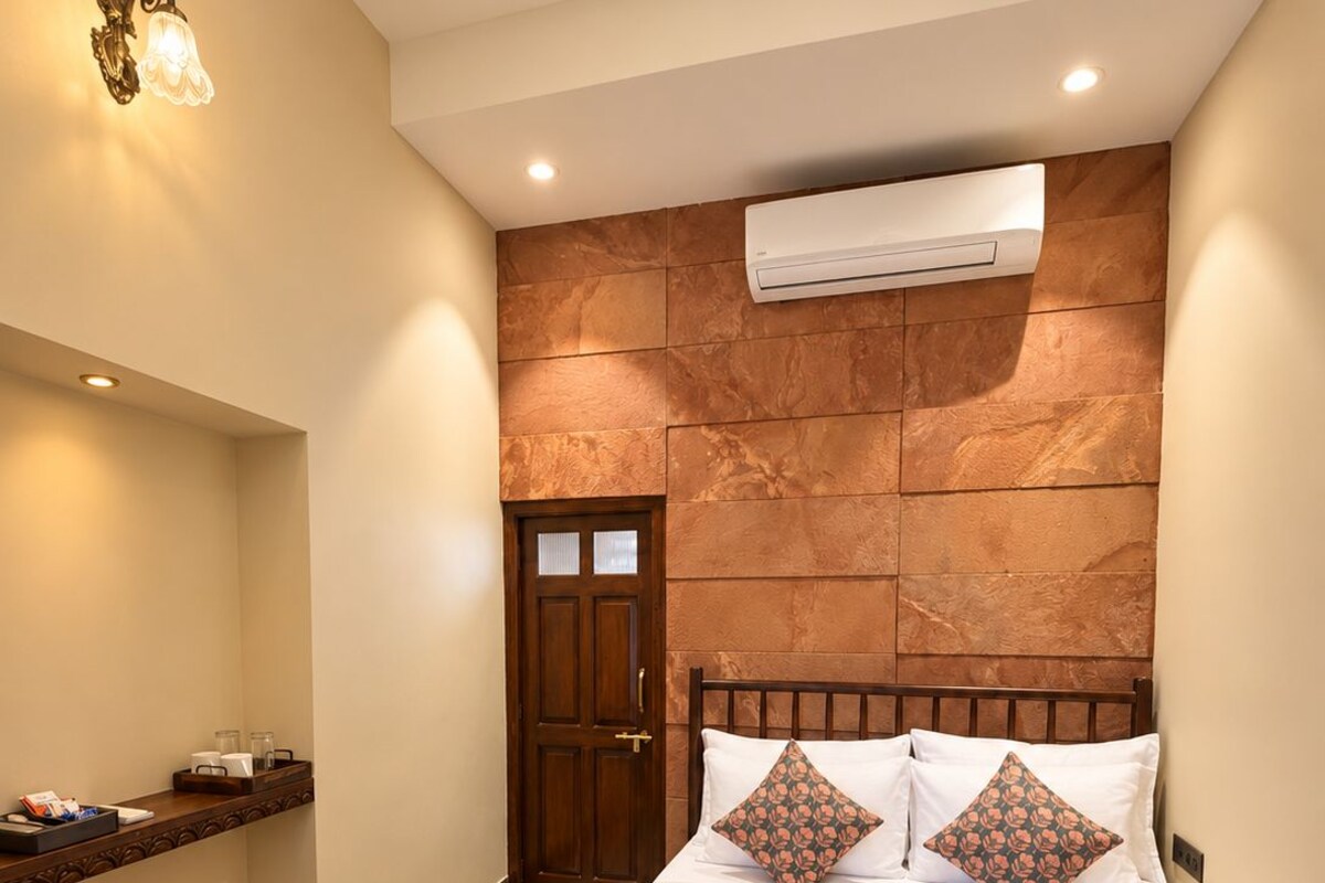 Une chambre d’hôtel équipée d’un lit, d’une table de chevet, d’un climatiseur fixé au mur et d’un comptoir d’enregistrement.