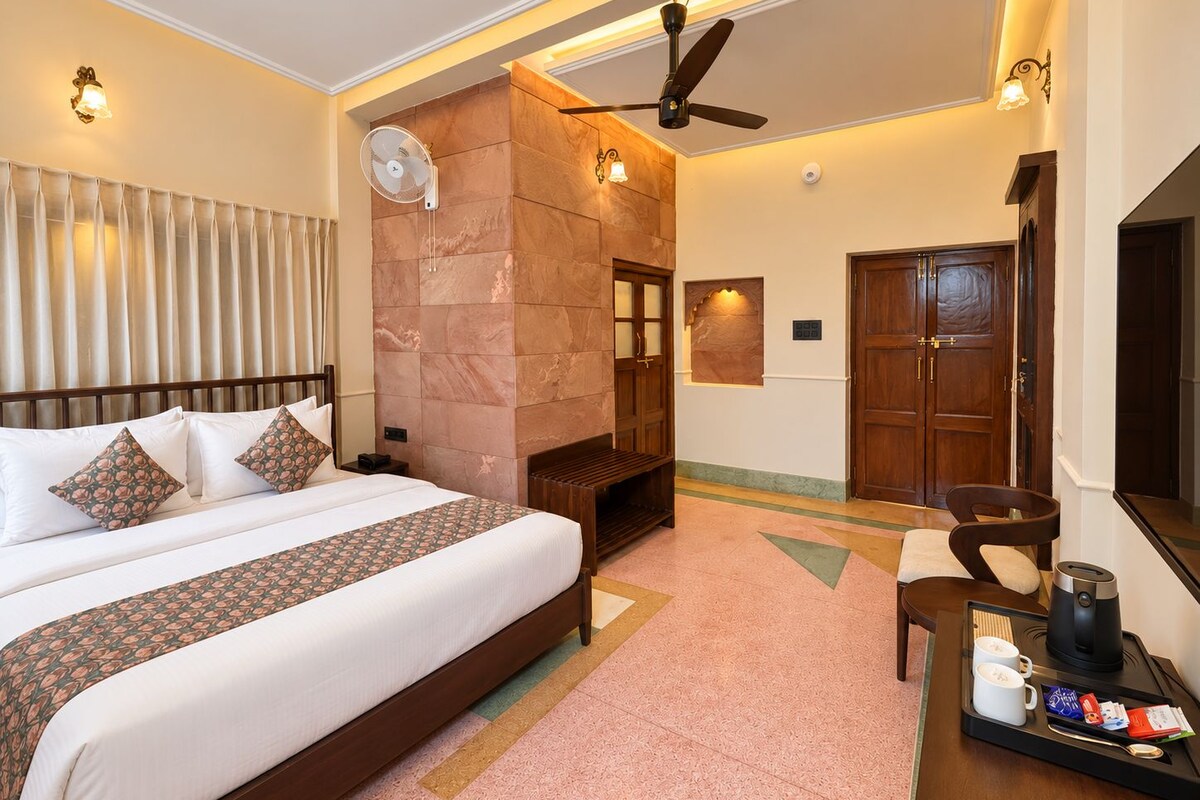 Une chambre d’hôtel comprenant un lit, un coin salon avec une table basse, une cheminée et un ventilateur de plafond.