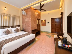 Une chambre d’hôtel comprenant un lit, un coin salon avec une table basse, une cheminée et un ventilateur de plafond.