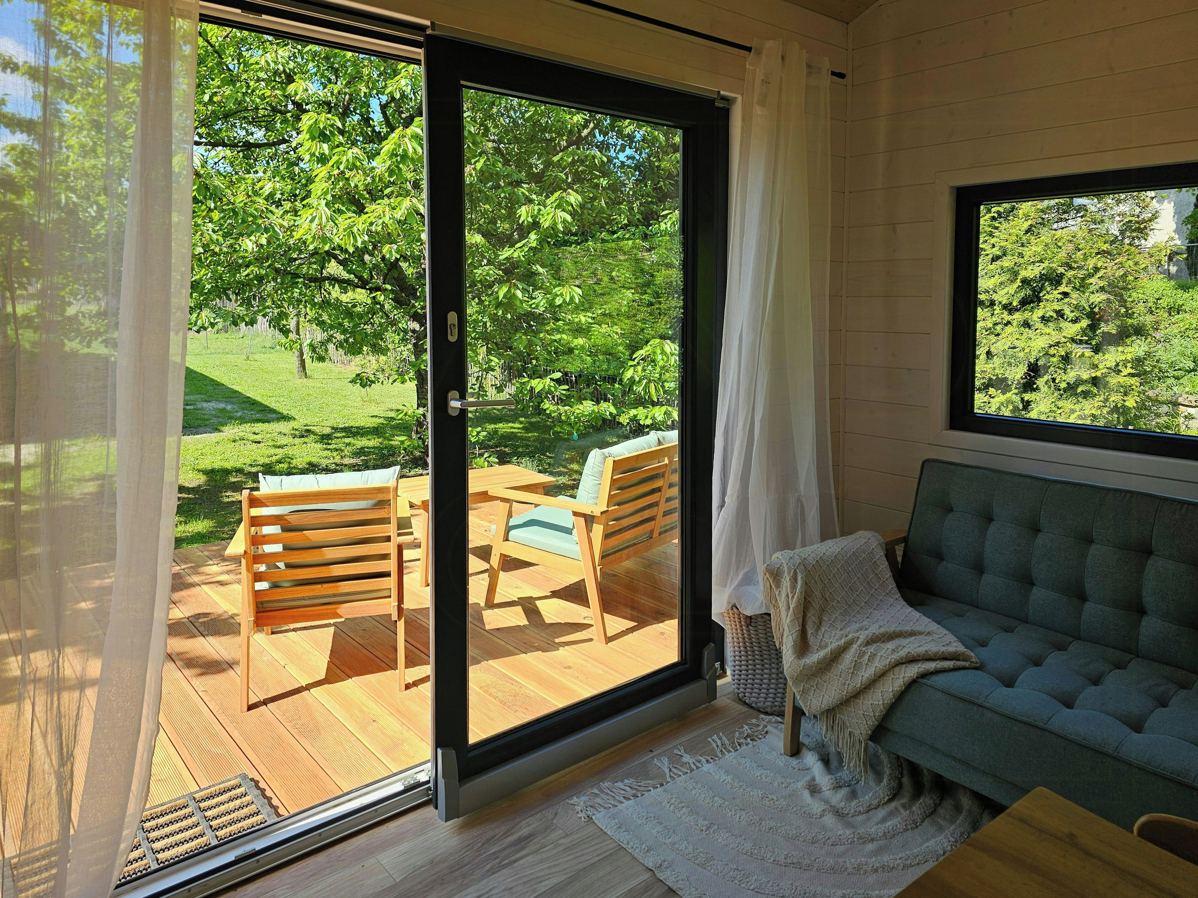 Ein Zimmer mit einer Schiebetür zum Gartenbereich, der Holzmöbel und einen Blick ins Grüne bietet.