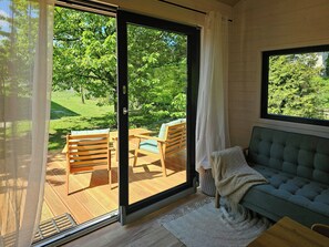 Ein Zimmer mit einer Schiebetür zum Gartenbereich, der Holzmöbel und einen Blick ins Grüne bietet.