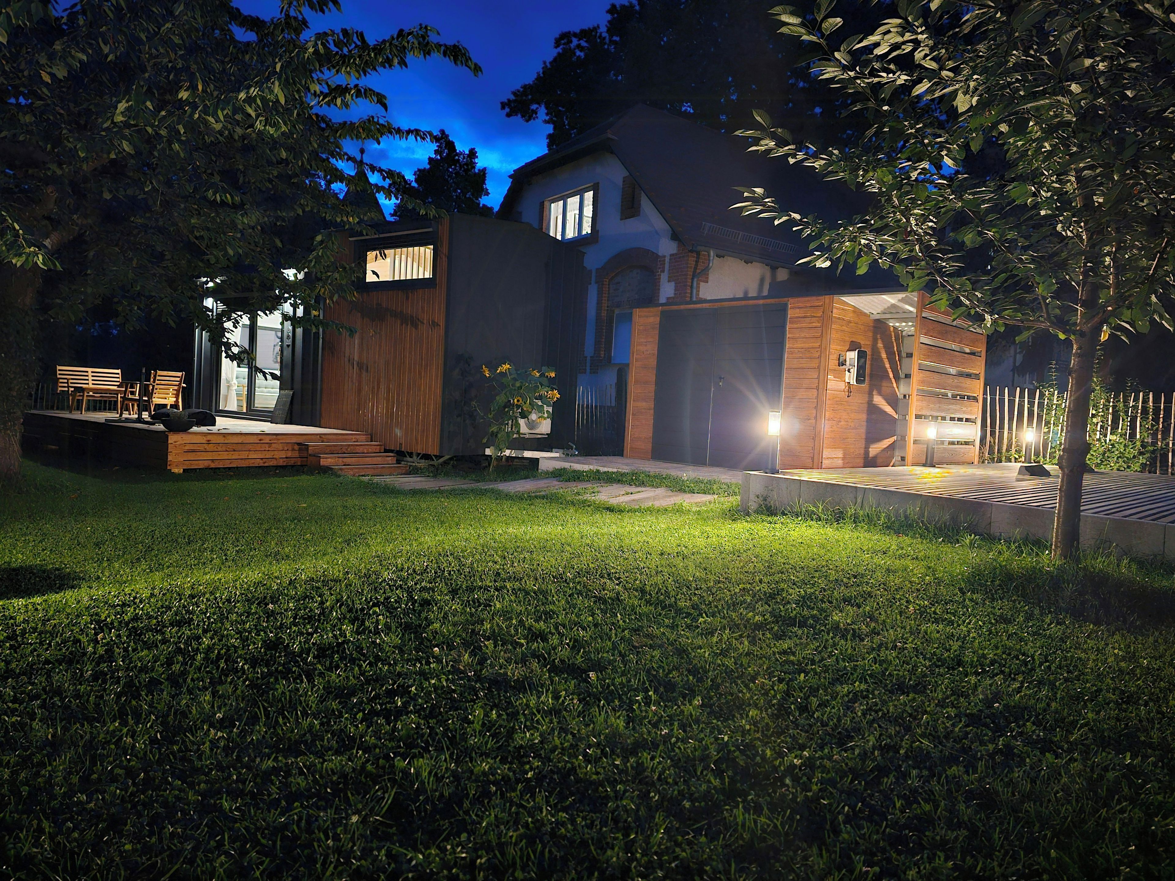 Een modern huis met een verzorgd gazon, een houten terras en een grote garage.