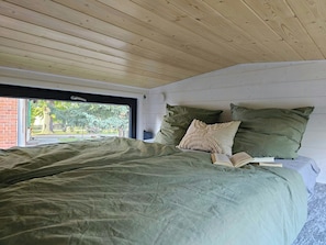Ein Schlafzimmer mit einem großen Bett, einem Fenster und Blick ins Freie.