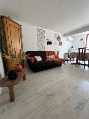 Una sala de estar con un sofá negro, una mesa de madera y paneles decorativos en la pared.