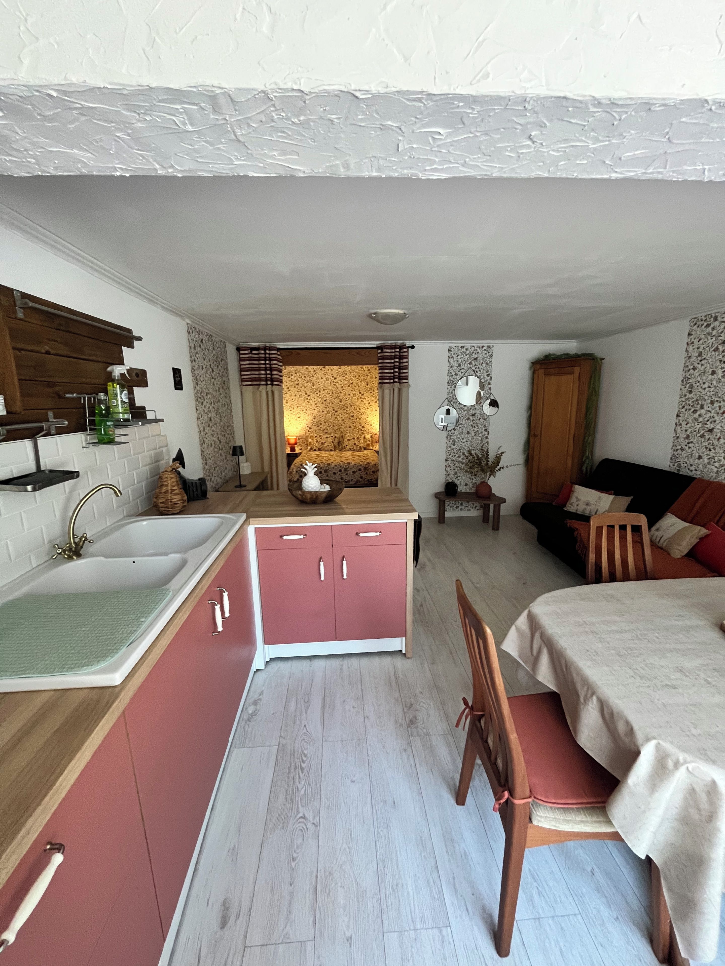 Een compacte leefruimte met een kitchenette, een eethoek en een zithoek met een bank en stoelen.
