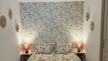 A bedroom with a patterned headboard, two bedside lamps, and a wooden floor.