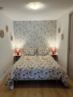 Un dormitorio con un cabecero estampado, dos lámparas de noche y suelo de madera.
