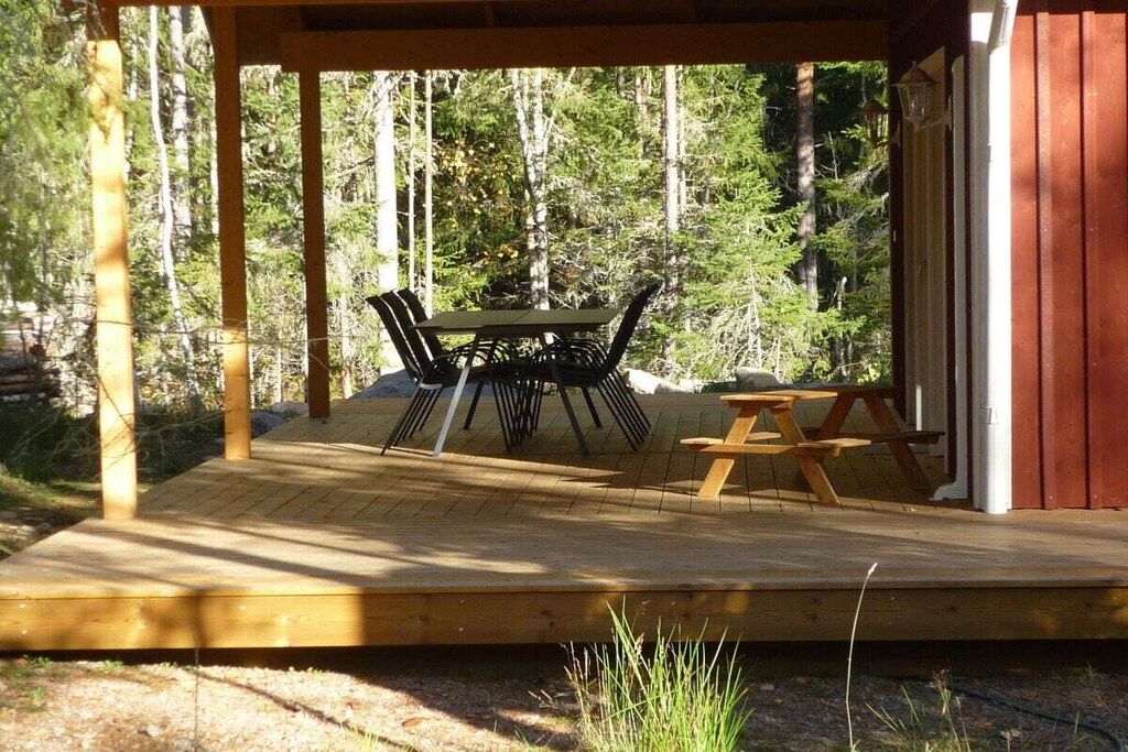 A wooden deck with a table and chairs, surrounded by trees.