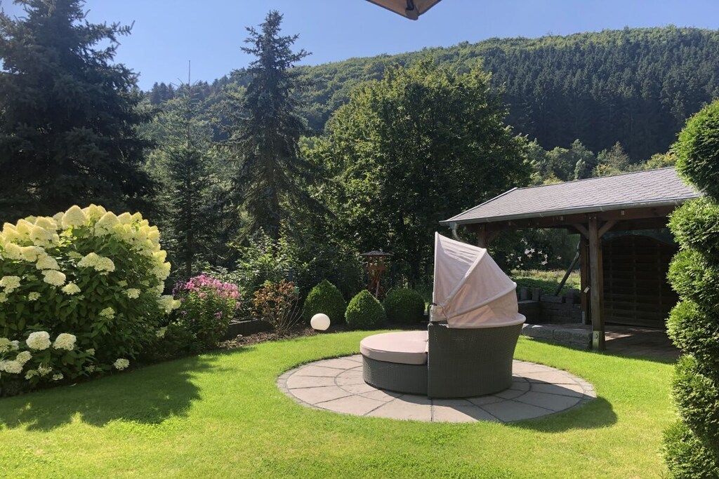 Un espace extérieur circulaire aménagé avec des sièges, une table couverte et un gazebo en arrière-plan.