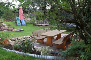 Een tuin met een picknicktafel, een glijbaan en een klein houten bouwwerk.