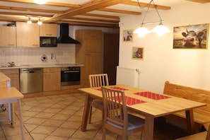 A kitchen with wooden cabinets, a microwave, a stove, and a dining table with chairs.