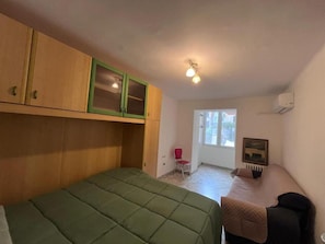 Ein Schlafzimmer mit einem Bett, einem Sessel, einem kleinen Tisch und einem Fenster.