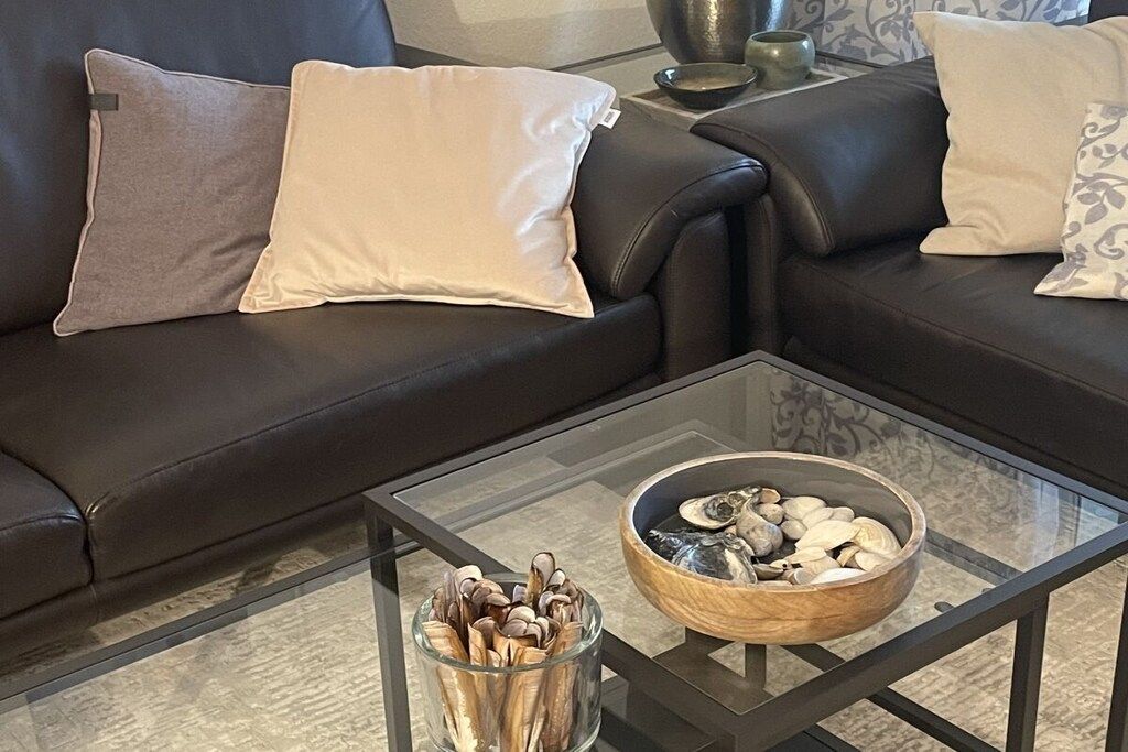 Un soggiorno con un tavolino in vetro, due divani e ciotole decorative.