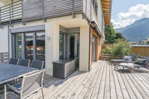 A modern outdoor deck with a dining area, a grill, and lounge seating.