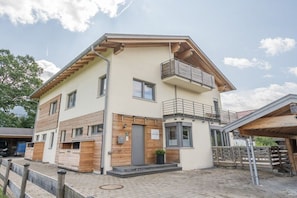 A two-story building with a balcony on the upper floor, a garage, and a paved driveway.