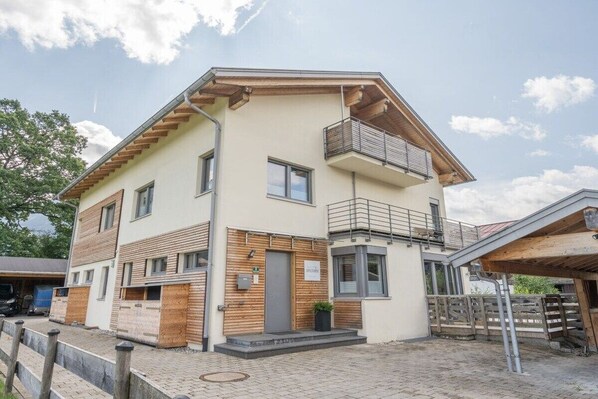 A two-story building with a balcony on the upper floor, a garage, and a paved driveway.