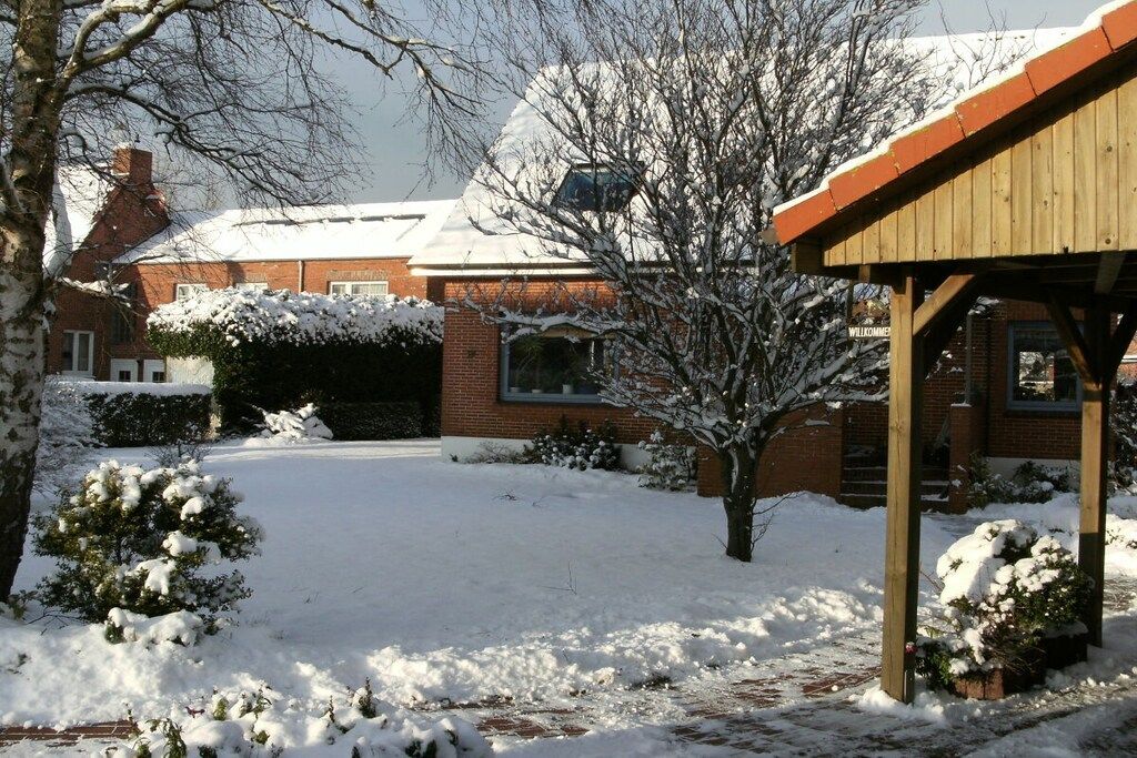 Un quartier résidentiel enneigé, avec une maison en briques, une structure en bois et de la neige au sol.
