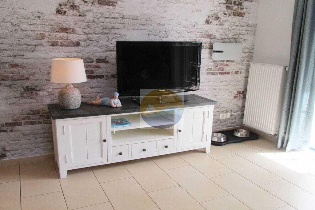 A living room with a white entertainment unit, a television, a lamp, and a small figurine.