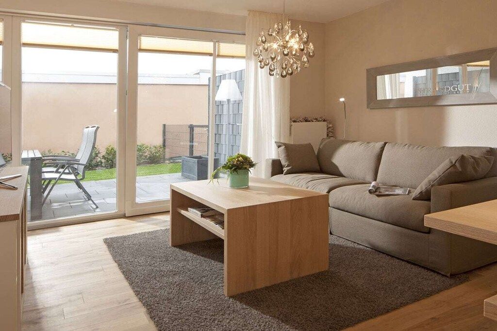 Un salon moderne avec un canapé, une table basse et un lustre.