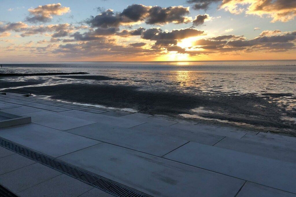 Une vue sur le coucher de soleil depuis une promenade en béton au bord de la mer.