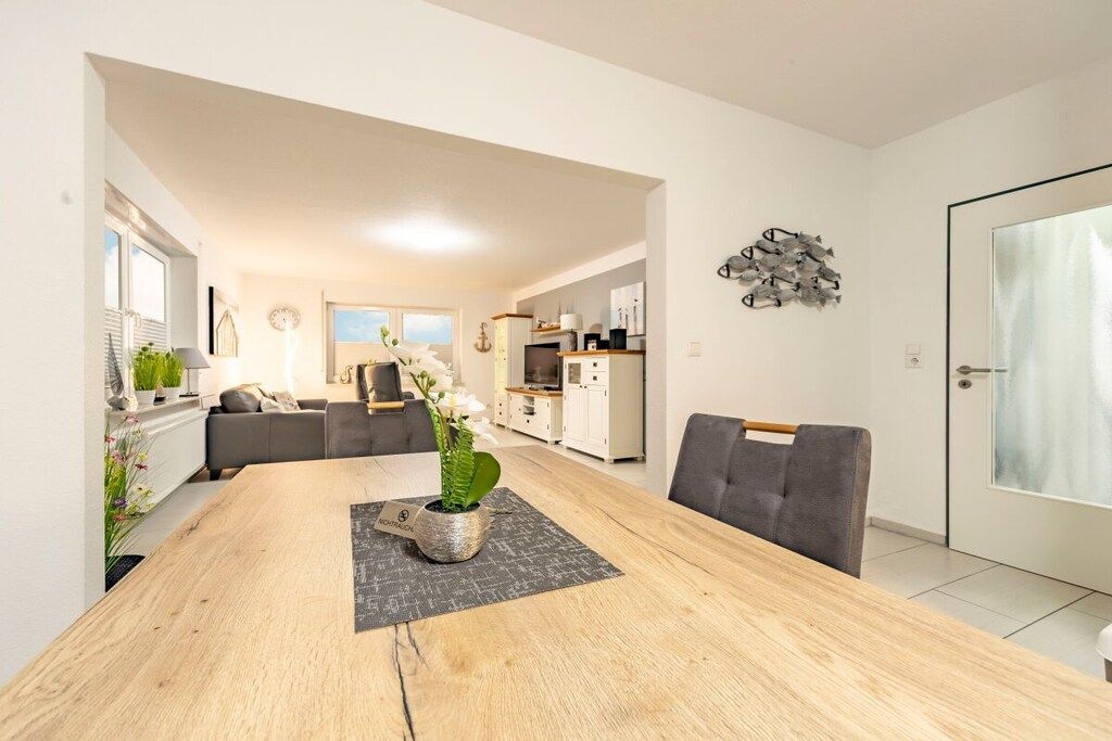 A modern living space with a dining table, sofa, kitchen area, and a door with a curtain.