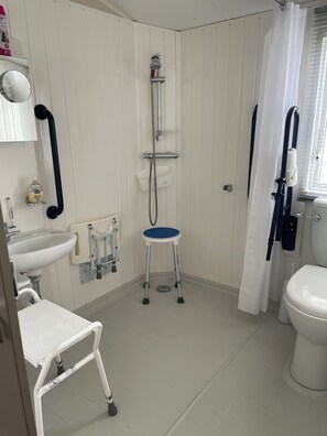 Ein Badezimmer mit Dusche, Toilette, Waschbecken und einer kleinen Stehlehre.