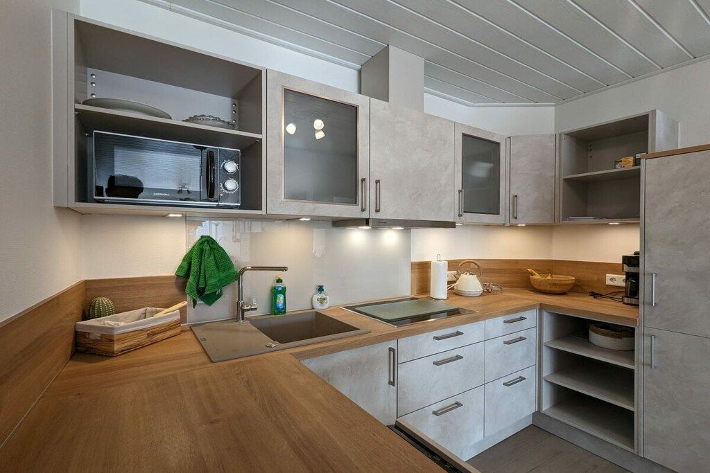 A modern kitchen with built-in appliances, a wooden countertop, and a sink.