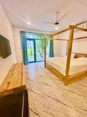 Un dormitorio con una cama con dosel, un escritorio de madera y vistas al exterior a través de un ventanal.