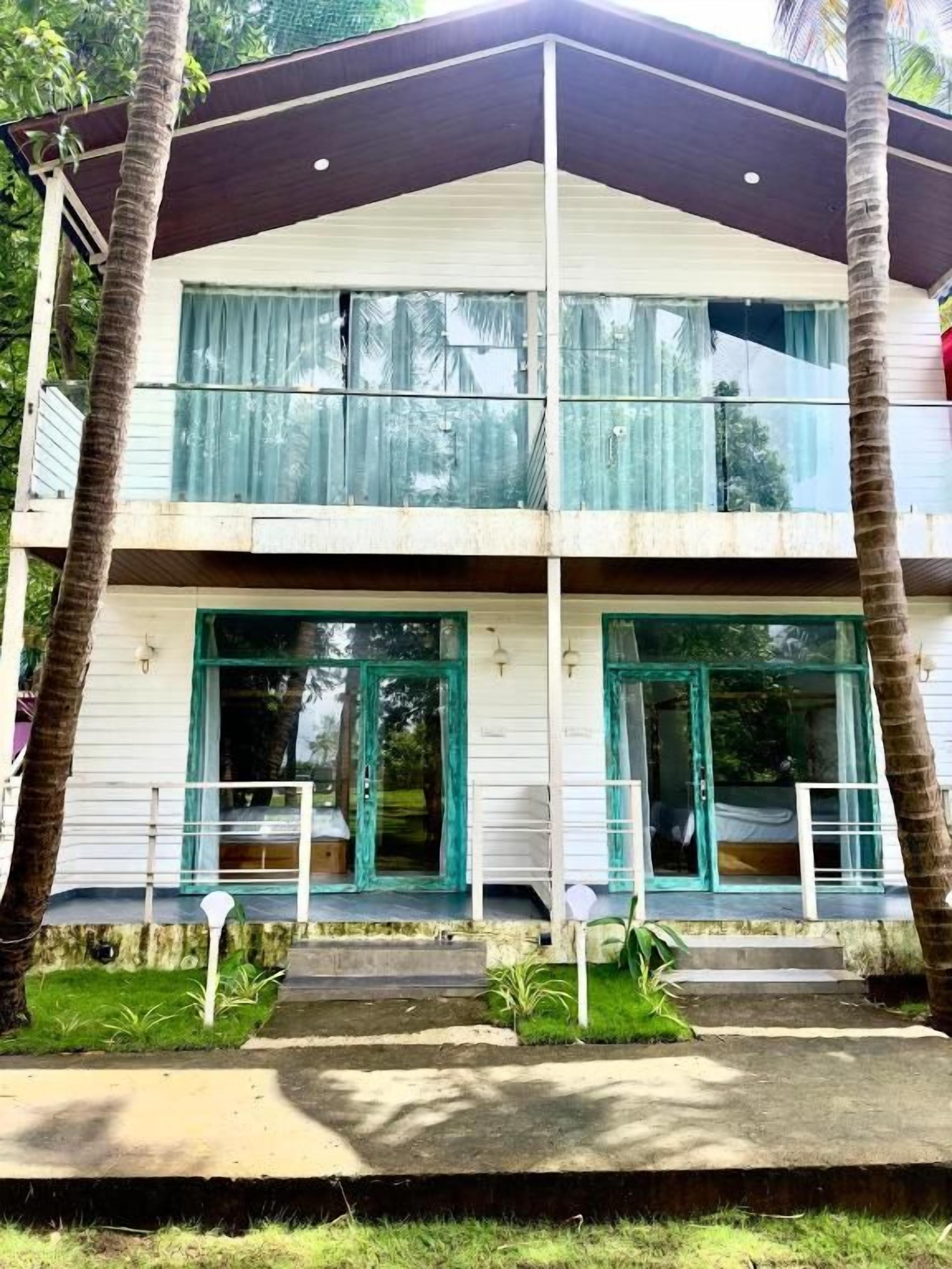 A two-story building with a balcony on the upper floor, a covered entrance, and a small porch area.