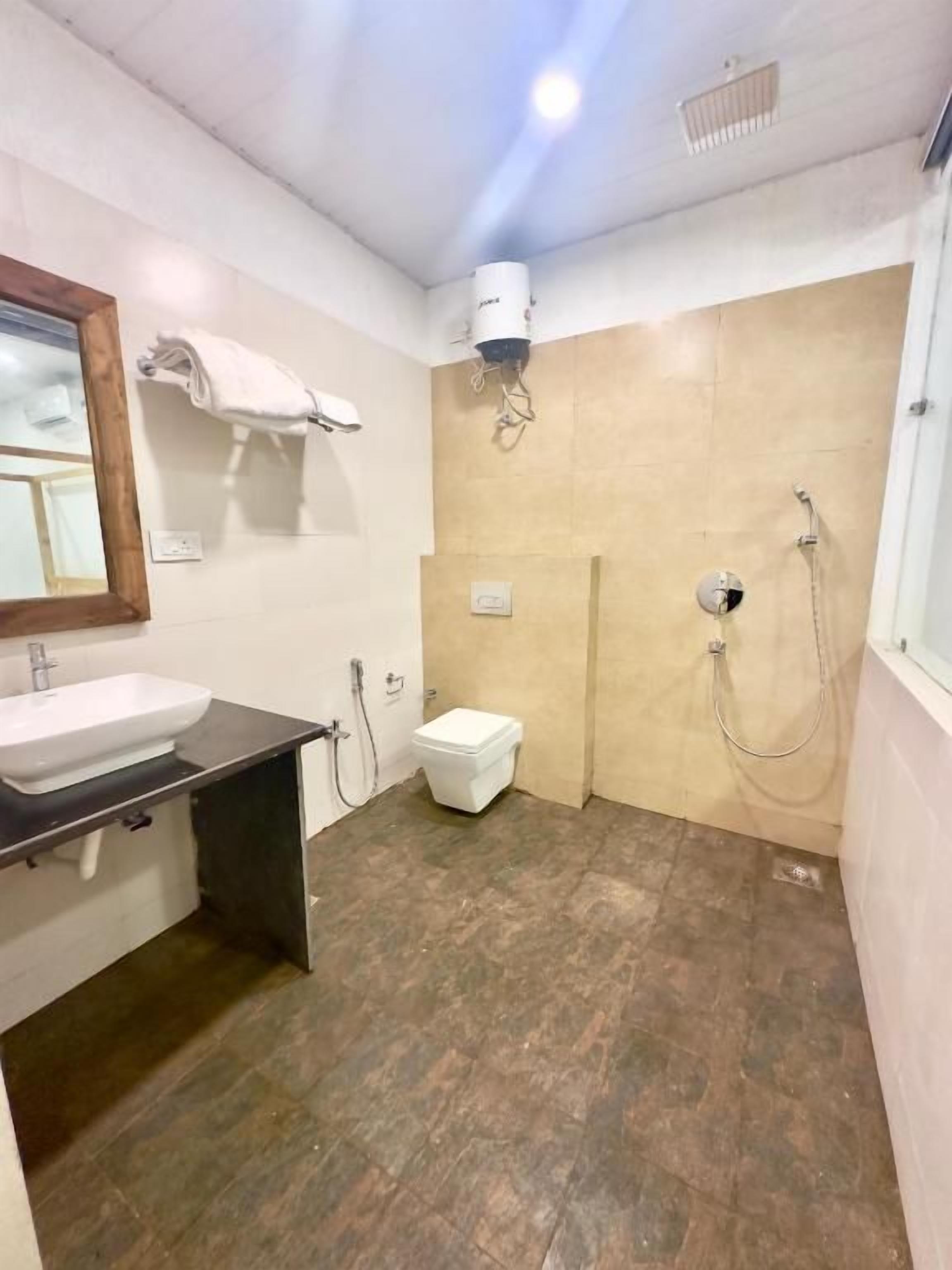 Un baño con lavamanos, inodoro, ducha y espejo.