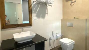 A bathroom with a black countertop sink, a white toilet, a mirror, and a towel rack.
