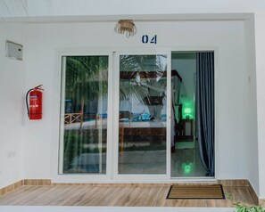 A hotel entrance with a glass door, a fire extinguisher, and a number '04' above the door. - Blue Roof Beach Bungalow (Matemwe Zanzibar north coast)