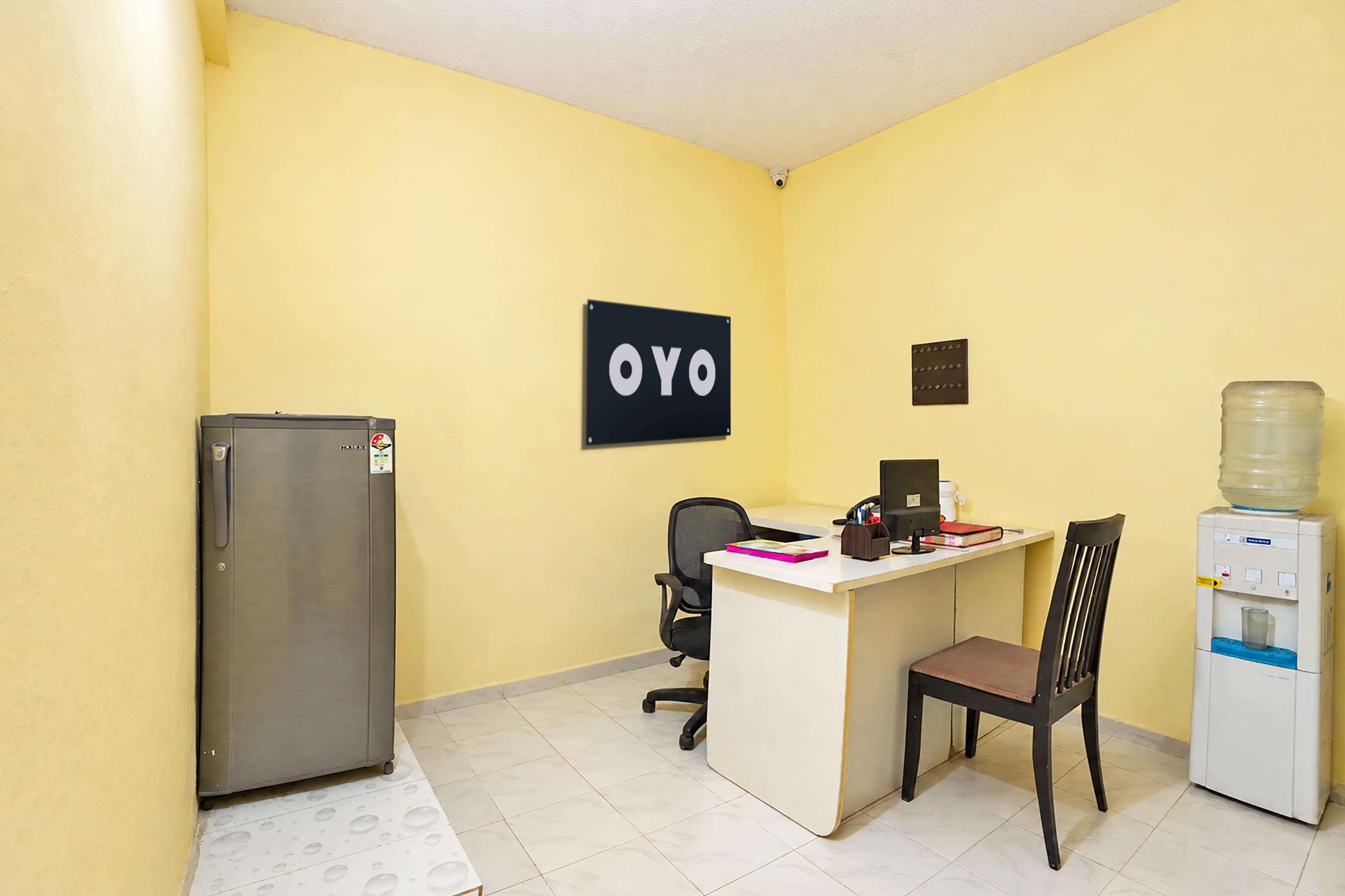 Un petit bureau équipé d’un bureau, d’une chaise, d’un ordinateur et d’un réfrigérateur.