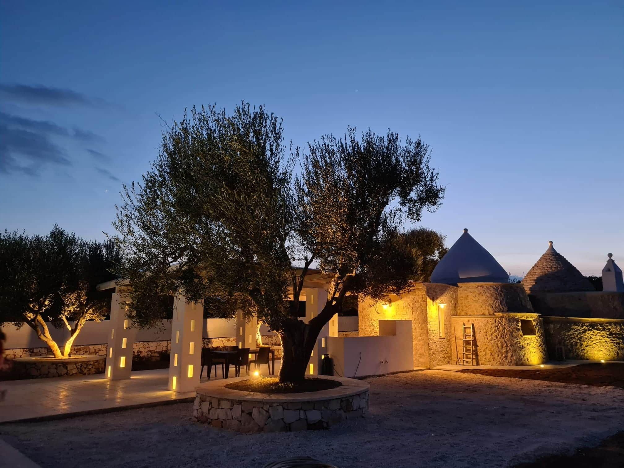 Un patio con un árbol, paredes de piedra y un edificio con cúpula.