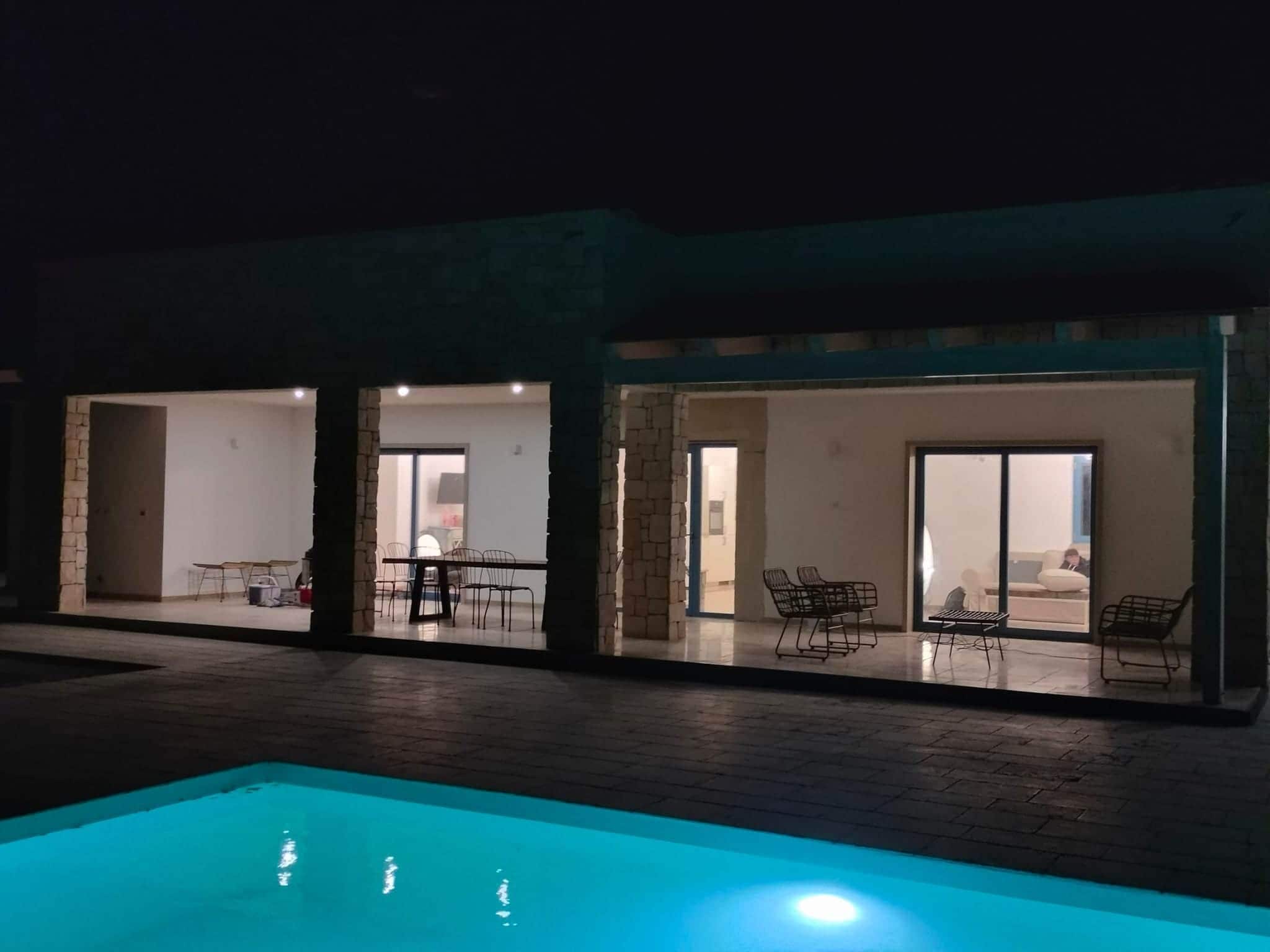 Zona de piscina con piscina, mobiliario exterior y un edificio con amplios ventanales.